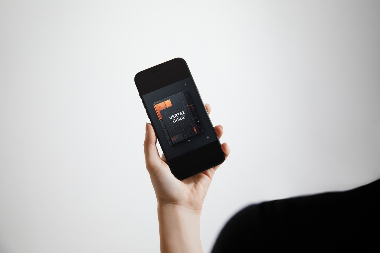A hand holding a black smartphone against a light gray background, with the phone screen displaying a dark interface and the text 'VERTEX EDITOR'.